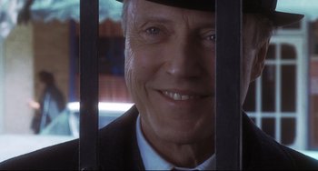 Movie still from “Catch Me If You Can” (2002), directed by Steven Spielberg – An older man wearing a black hat and a suit; Close Up shot, Low angle