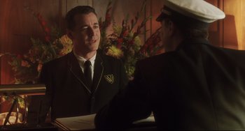 Movie still from “Catch Me If You Can” (2002), directed by Steven Spielberg – A man wearing a suit and tie talking to another man wearing a hat; Medium shot, Low angle