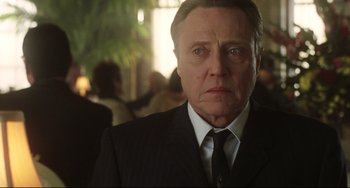 Movie still from “Catch Me If You Can” (2002), directed by Steven Spielberg – An older man in a suit and tie looking sad; Close Up shot, Low angle