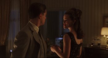 Movie still from “Catch Me If You Can” (2002), directed by Steven Spielberg – A man and a woman standing next to each other in a room; Medium shot, Over the shoulder angle