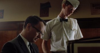 Movie still from “Catch Me If You Can” (2002), directed by Steven Spielberg – A man in a suit and tie next to a man in a bow tie; Medium shot, Low angle