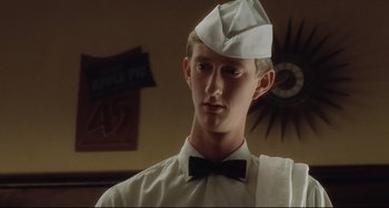 Movie still from “Catch Me If You Can” (2002), directed by Steven Spielberg – A man wearing a paper hat and a bow tie; Close Up shot, Low angle