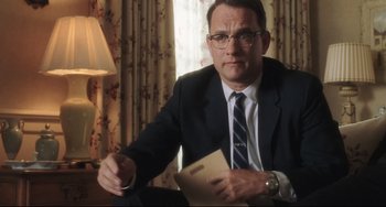 Movie still from “Catch Me If You Can” (2002), directed by Steven Spielberg – A man in a suit and tie holding a paper; Close Up shot, Over the shoulder angle