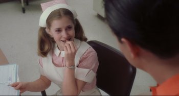 Movie still from “Catch Me If You Can” (2002), directed by Steven Spielberg – A young girl in a nurse's uniform is sitting in front of a young man; Medium shot, Over the shoulder angle