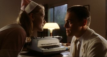 Movie still from “Catch Me If You Can” (2002), directed by Steven Spielberg – A man and a woman looking at each other with a typewriter; Close Up shot, Low angle