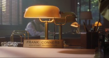 Movie still from “Catch Me If You Can” (2002), directed by Steven Spielberg – A desk lamp sitting on top of a desk; Medium shot, High angle