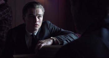 Movie still from “Catch Me If You Can” (2002), directed by Steven Spielberg – A man in a suit and tie sitting in front of a mirror; Close Up shot, Over the shoulder angle