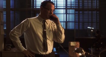 Movie still from “Catch Me If You Can” (2002), directed by Steven Spielberg – An older man talking on a phone in a room; Medium shot, Low angle