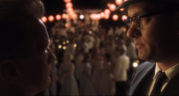 Movie still from “Catch Me If You Can” (2002), directed by Steven Spielberg – Two men are standing in front of a crowd of people; Close Up shot, Over the shoulder angle