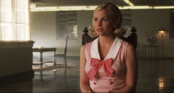 Movie still from “Catch Me If You Can” (2002), directed by Steven Spielberg – A woman wearing a pink dress with a pink bow in a room; Close Up shot, Over the shoulder angle