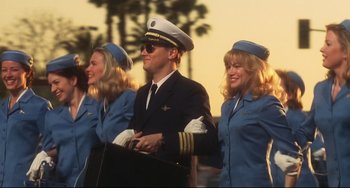 Movie still from “Catch Me If You Can” (2002), directed by Steven Spielberg – A man in a pilot's uniform standing next to two women in blue uniforms; Medium shot, Low angle