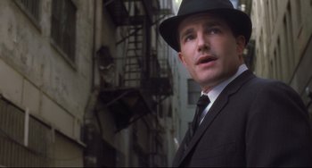 Movie still from “Catch Me If You Can” (2002), directed by Steven Spielberg – A man wearing a suit and a hat standing in front of a fire escape; Close Up shot, Low angle