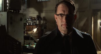 Movie still from “Catch Me If You Can” (2002), directed by Steven Spielberg – A man wearing glasses and a tie in a room; Close Up shot, Low angle