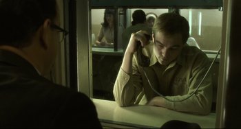 Movie still from “Catch Me If You Can” (2002), directed by Steven Spielberg – A man sitting in front of a window on a train; Medium shot, Over the shoulder angle