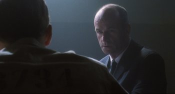 Movie still from “Catch Me If You Can” (2002), directed by Steven Spielberg – A man wearing a suit and tie talking to another man in front of a mirror; Close Up shot, Over the shoulder angle