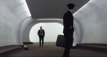 Movie still from “Catch Me If You Can” (2002), directed by Steven Spielberg – A man in a suit and tie holding a briefcase in front of another man in a suit and tie; Wide shot, Low angle
