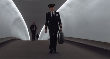 Movie still from “Catch Me If You Can” (2002), directed by Steven Spielberg – A man in a suit and tie holding a briefcase; Wide shot, Low angle