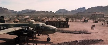 Movie still from “Catch-22” (1970), directed by Mike Nichols – An airplane parked in a field with tents in the background; Extreme Wide shot, Low angle