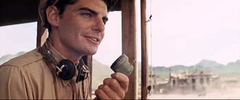 Movie still from “Catch-22” (1970), directed by Mike Nichols – A man with headphones holding up a camera; Close Up shot, Low angle