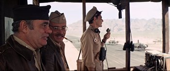 Movie still from “Catch-22” (1970), directed by Mike Nichols – A couple of men are standing next to each other; Medium shot, Low angle
