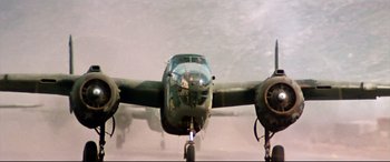 Movie still from “Catch-22” (1970), directed by Mike Nichols – An airplane is flying through the air on a cloudy day; Wide shot, Low angle