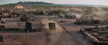 Movie still from “Catch-22” (1970), directed by Mike Nichols – A truck driving down a dirt road near some tents; Extreme Wide shot, High angle
