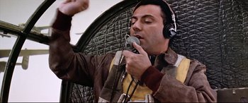 Movie still from “Catch-22” (1970), directed by Mike Nichols – A man with a microphone in his hand; Close Up shot, Low angle