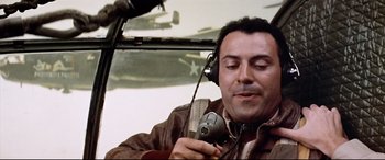 Movie still from “Catch-22” (1970), directed by Mike Nichols – A man in a brown jacket holding an old camera; Close Up shot, Low angle