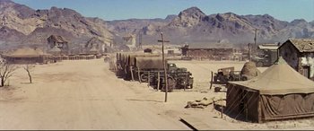 Movie still from “Catch-22” (1970), directed by Mike Nichols – An old truck is parked in the dirt; Extreme Wide shot, High angle