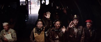 Movie still from “Catch-22” (1970), directed by Mike Nichols – A group of men standing next to each other waving; Medium shot, High angle