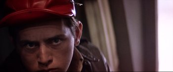 Movie still from “Catch-22” (1970), directed by Mike Nichols – A young man wearing a red hat and a brown jacket; Close Up shot, Low angle