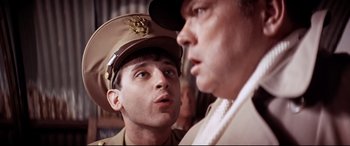 Movie still from “Catch-22” (1970), directed by Mike Nichols – A man in a military uniform talking to another man; Close Up shot, Over the shoulder angle