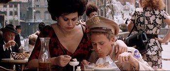 Movie still from “Catch-22” (1970), directed by Mike Nichols – A man and a woman sitting at a table eating food; Medium shot, High angle