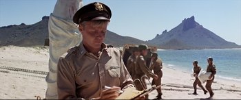 Movie still from “Catch-22” (1970), directed by Mike Nichols – A man in a military uniform writing on a piece of paper; Medium shot, Low angle