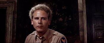 Movie still from “Catch-22” (1970), directed by Mike Nichols – A man in a military uniform with blonde curly hair; Close Up shot, Low angle