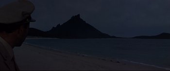 Movie still from “Catch-22” (1970), directed by Mike Nichols – A beach at night with a mountain in the background; Extreme Wide shot, Low angle