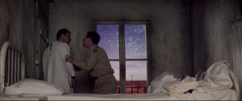 Movie still from “Catch-22” (1970), directed by Mike Nichols – Two men in uniform standing in front of a window; Medium shot, Low angle