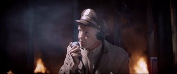 Movie still from “Catch-22” (1970), directed by Mike Nichols – A man wearing a hat is holding a microphone; Close Up shot, Low angle