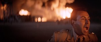 Movie still from “Catch-22” (1970), directed by Mike Nichols – A person standing in front of a burning building; Close Up shot, Low angle