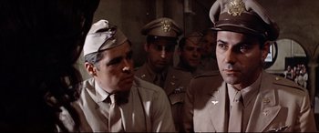 Movie still from “Catch-22” (1970), directed by Mike Nichols – A group of men in uniform sitting next to each other; Medium shot, Low angle