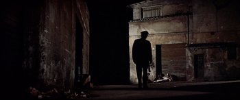 Movie still from “Catch-22” (1970), directed by Mike Nichols – A man standing in the dark holding a skateboard; Wide shot, Low angle