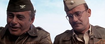 Movie still from “Catch-22” (1970), directed by Mike Nichols – A couple of men in military uniforms standing next to each other; Close Up shot, Low angle
