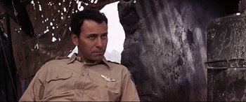 Movie still from “Catch-22” (1970), directed by Mike Nichols – A man in a tan uniform standing in front of a rock wall; Close Up shot, Low angle