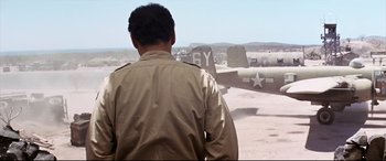 Movie still from “Catch-22” (1970), directed by Mike Nichols – A man in a field looking at an old fighter plane; Wide shot, Over the shoulder angle