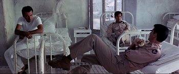 Movie still from “Catch-22” (1970), directed by Mike Nichols – A man sitting on a hospital bed in a room; Wide shot, Low angle