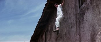Movie still from “Catch-22” (1970), directed by Mike Nichols – A man in a white shirt is doing a trick in the air; Wide shot, Low angle