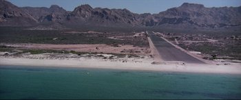Movie still from “Catch-22” (1970), directed by Mike Nichols – An aerial view of an airport runway near the ocean; Extreme Wide shot, High angle