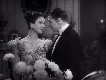 Movie still from “Cavalcade” (1933), directed by Frank Lloyd – A man and a woman standing next to each other in formal wear; Medium shot, High angle