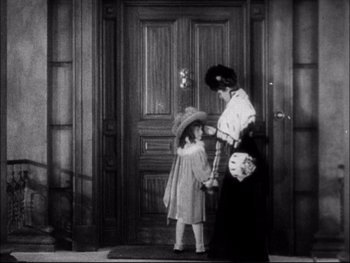 Movie still from “Cavalcade” (1933), directed by Frank Lloyd – An old photo of a woman and a little girl standing in front of a door; Medium shot, High angle