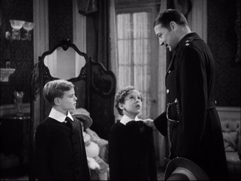 Movie still from “Cavalcade” (1933), directed by Frank Lloyd – A man and two young boys standing next to each other in a room; Medium shot, Over the shoulder angle